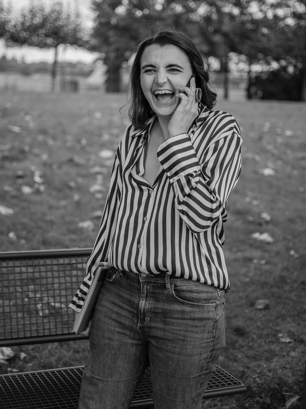 Black and white portrait of person laughing in striped shirt outdoors.