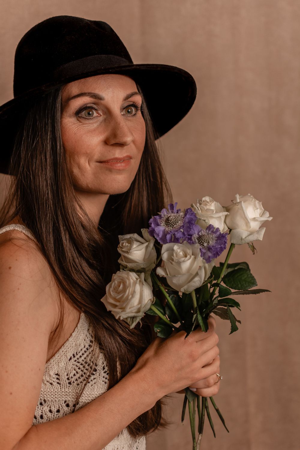 Romantic portrait with black hat and mixed white and purple flower bouquet.