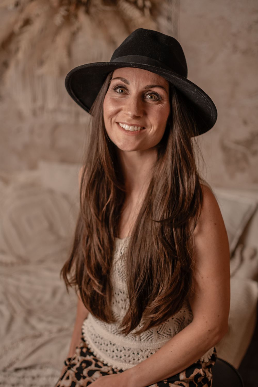 Lifestyle portrait featuring black hat, lace top and leopard print skirt in warm tones.