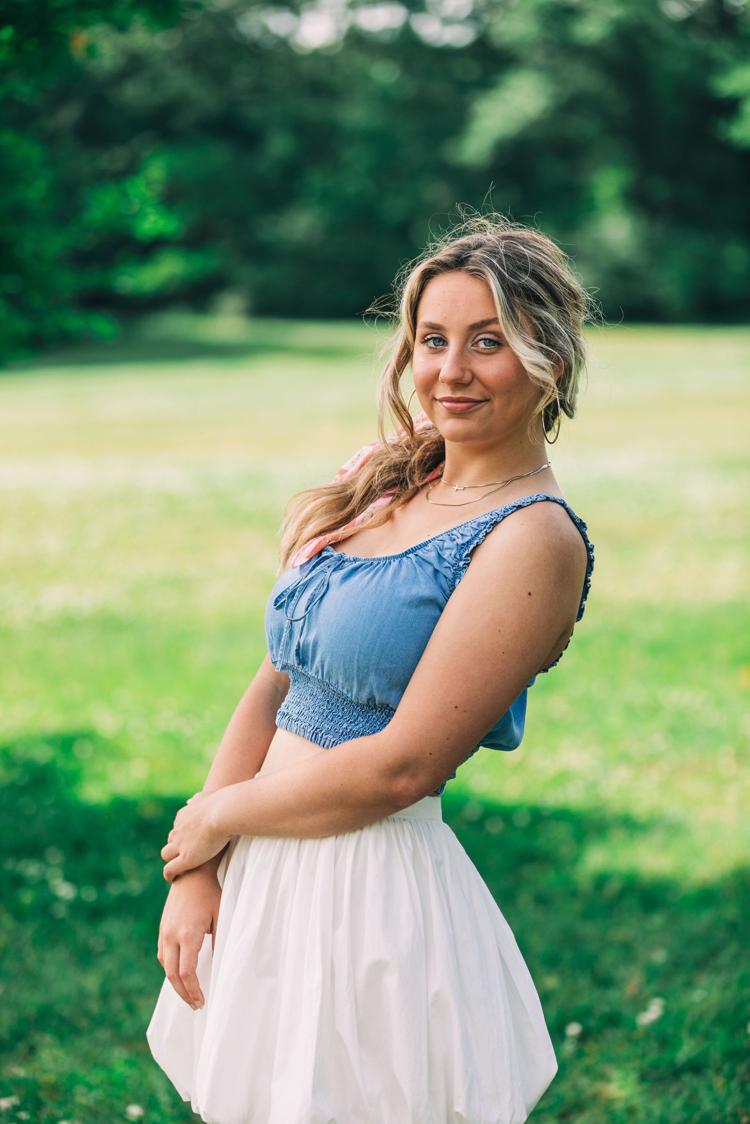 Summer fashion portrait in blue crop top and white skirt outdoors.