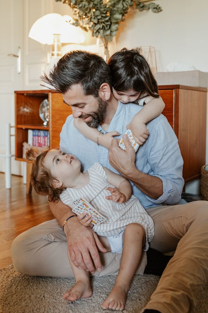 papa joue avec ses filles pendant une séance photo grossesse en famille à domicile à Lille