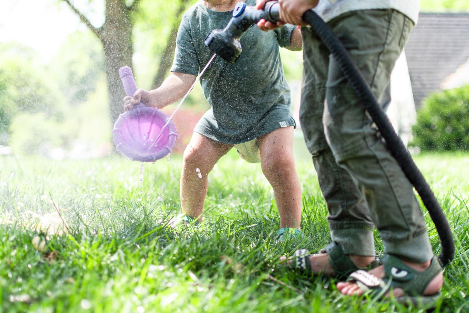 Brothers play with the water hose in their front yard in Ardmore Historical District.