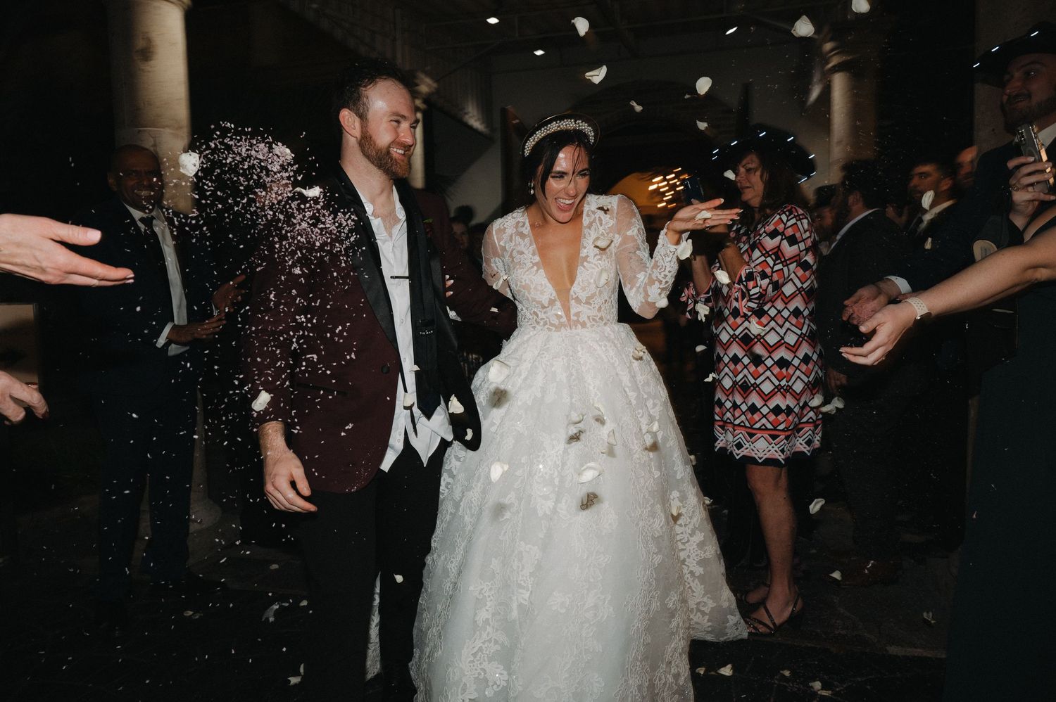 Wedding couple celebrates amid falling confetti during indoor reception.