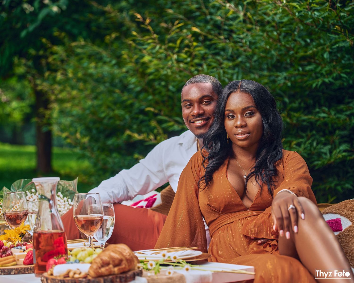 Romantic outdoor picnic photoshoot of a stylish couple enjoying a luxury dining experience in nature.