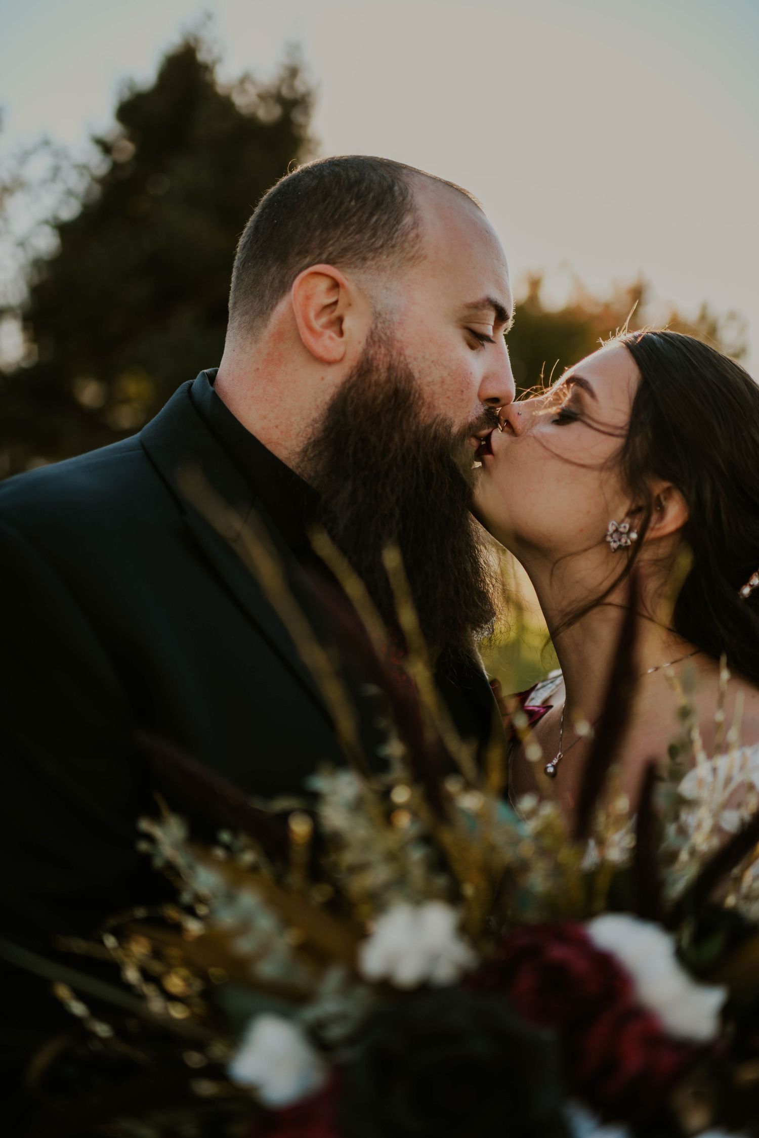 Romantic sunset kiss captured in silhouette with golden hour lighting.