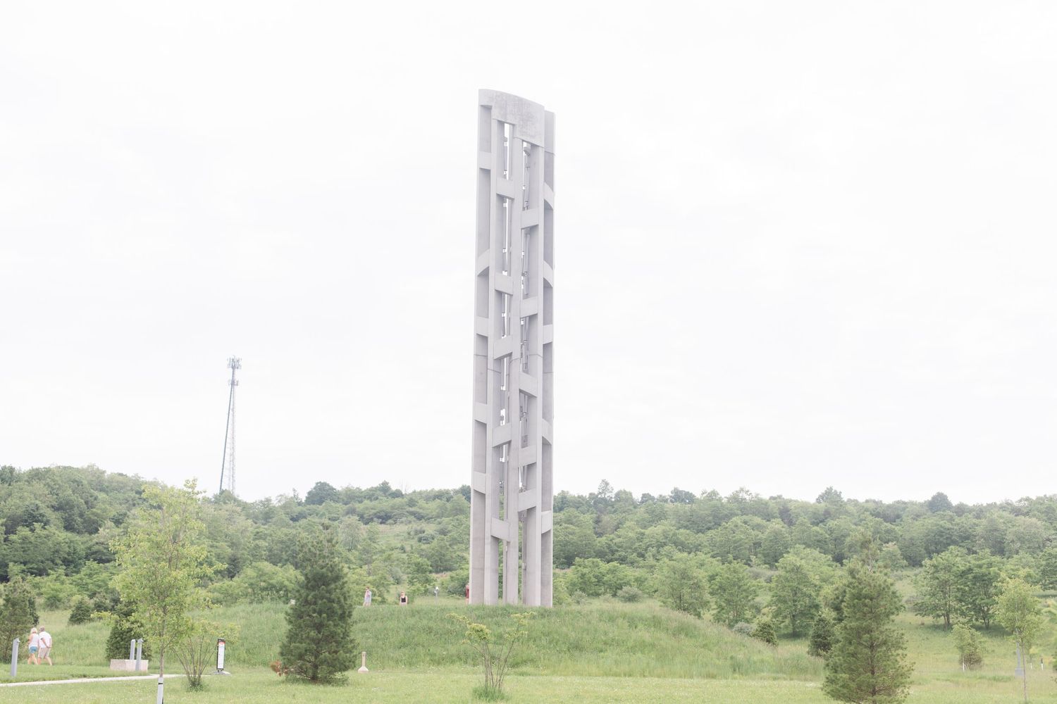 Tall white Tower of Voices memorial structure rising above green rolling hills.