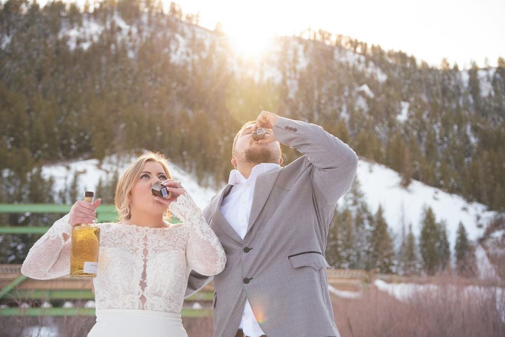 winter bride and groom doing shots of whiskey at sunset