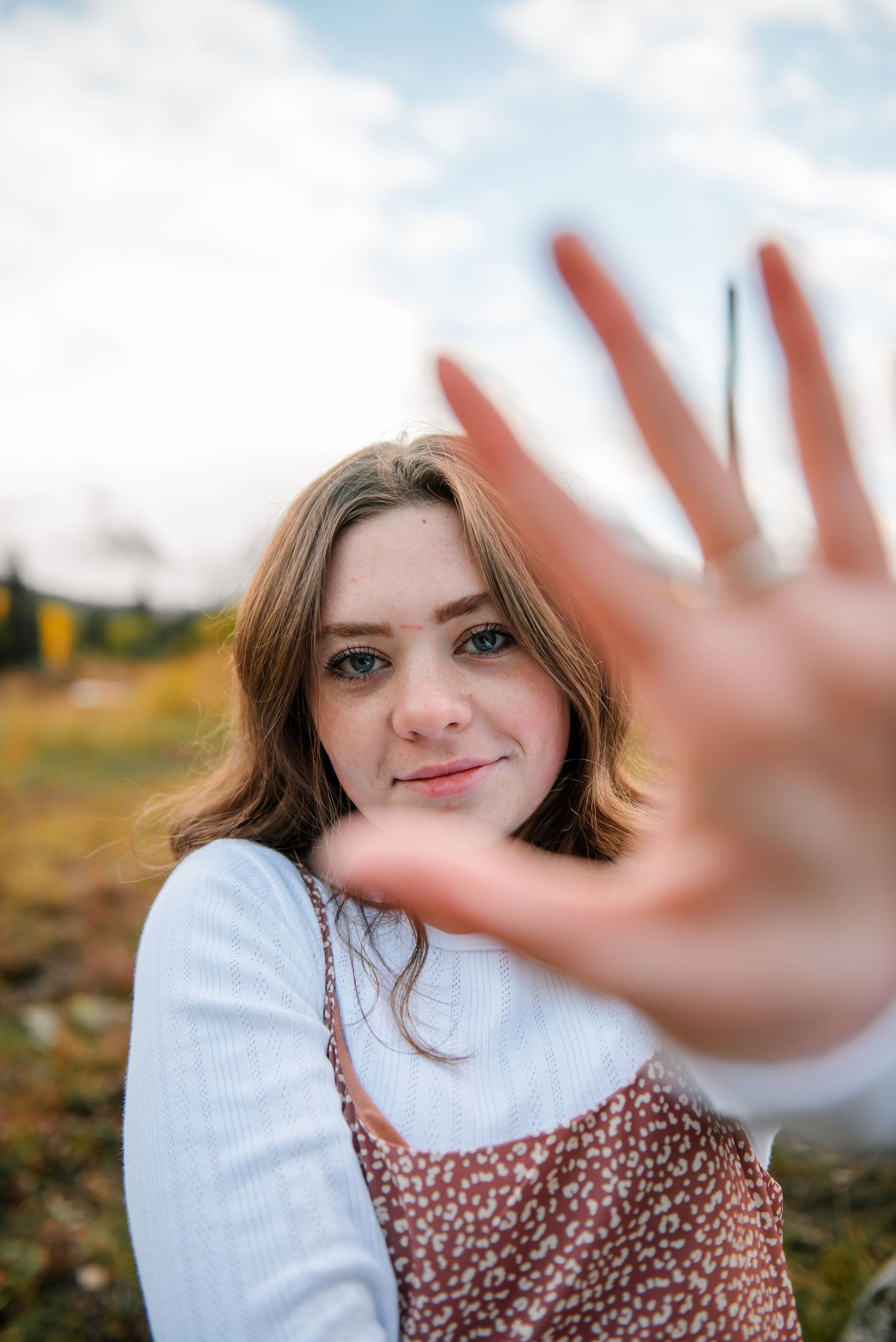 Playful portrait in a field with mountains and autumn colors in background.