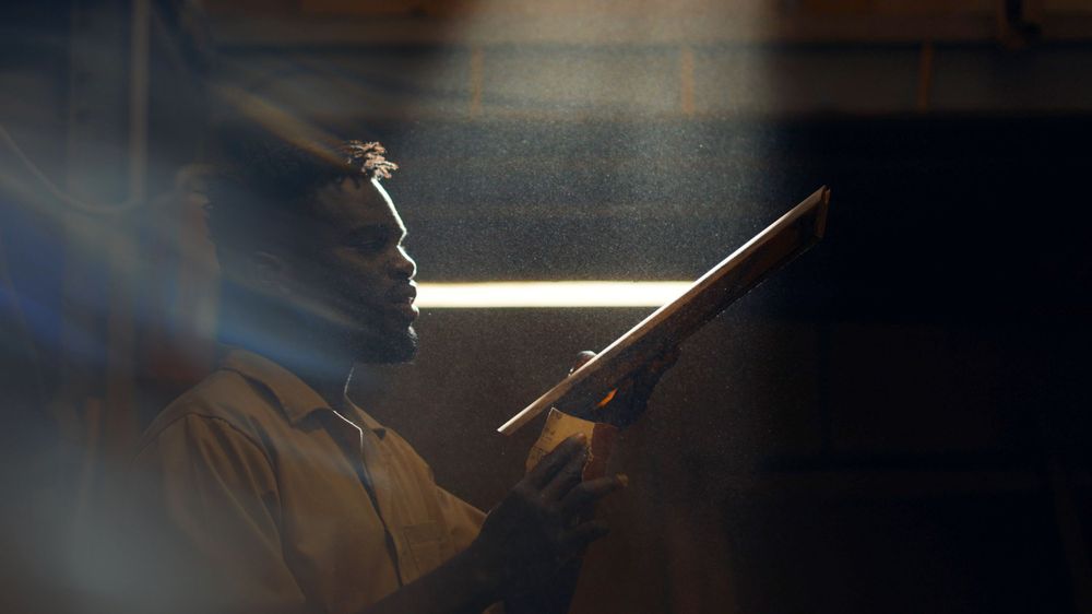 Silhouette of someone working with tools in dramatic lighting conditions.