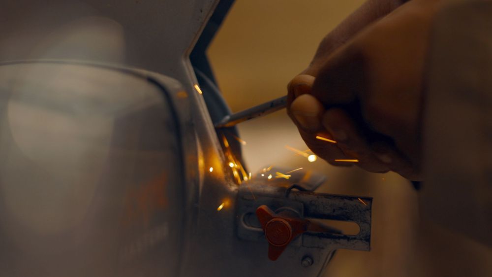 Hand using tools to work on detailed mechanisms in close-up shot.