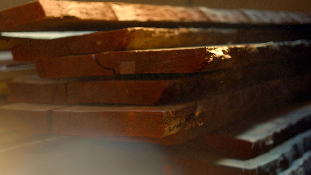 Stack of weathered wooden boards illuminated by warm golden light.