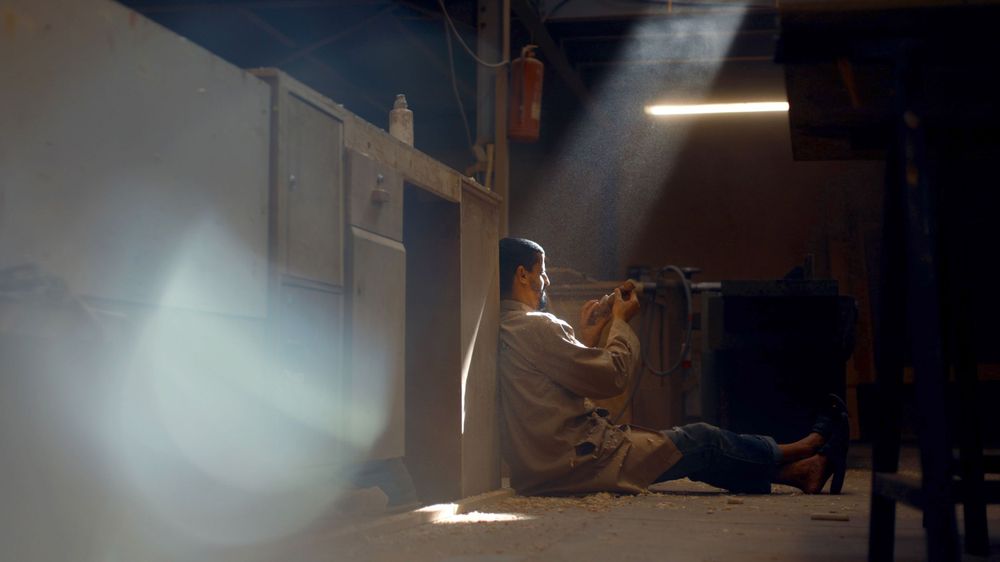 Person sitting alone in a ray of sunlight streaming through a window.