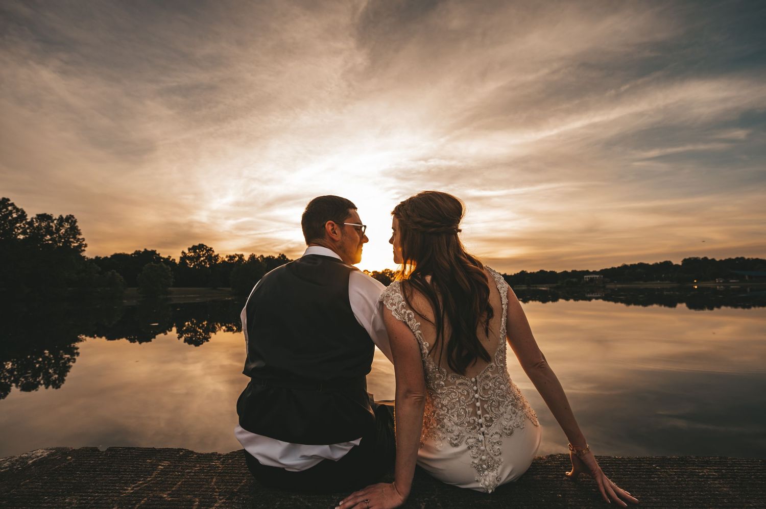 Dramatic sunset silhouette wedding photos with golden sky and natural landscape.