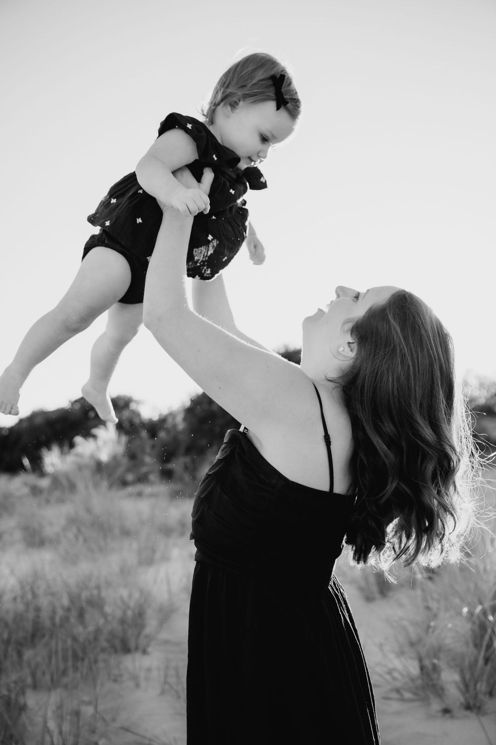 Black and white photo capturing a joyful moment of lifting and playing on the beach. third beach middletown rhode island