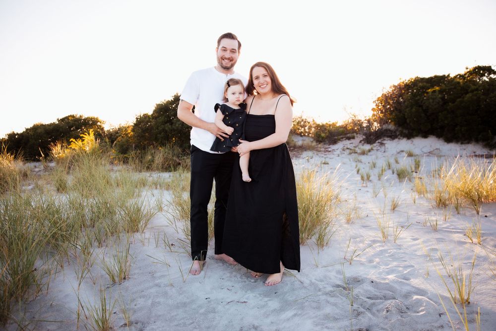 Family portrait on sandy dunes at sunset wearing coordinated black and white outfits. third beach middletown rhode island