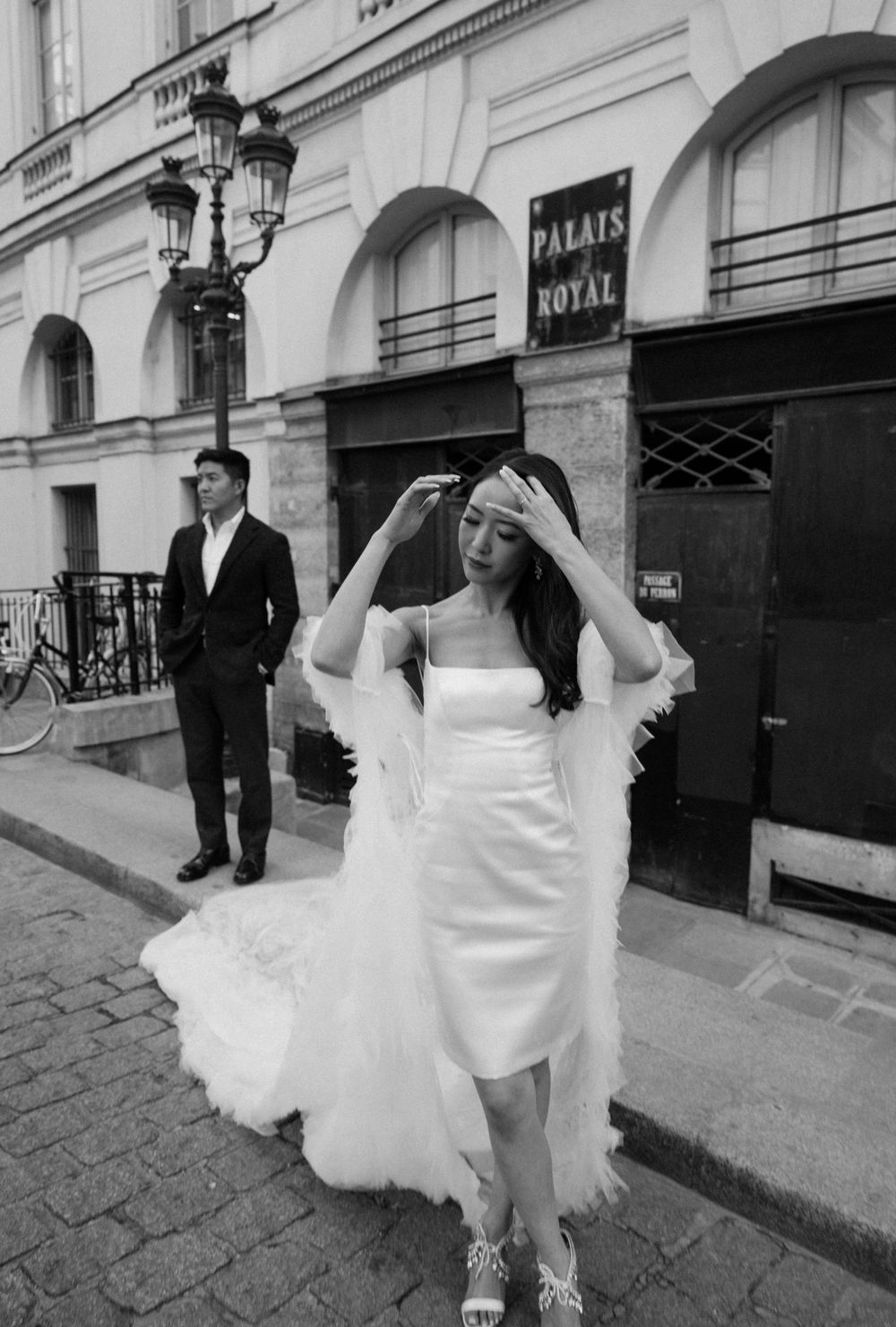Black and white bridal portrait outside Palais Royal featuring short wedding dress with flowing train.