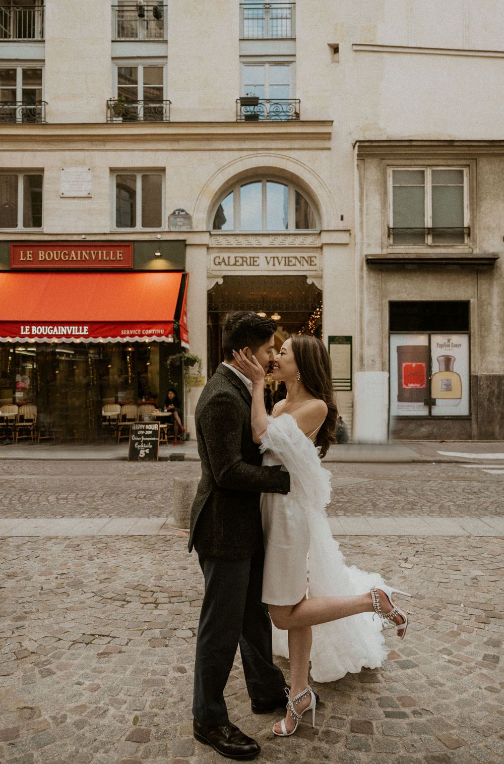 A romantic embrace outside a Parisian cafe with charming cobblestone streets and classic architecture.