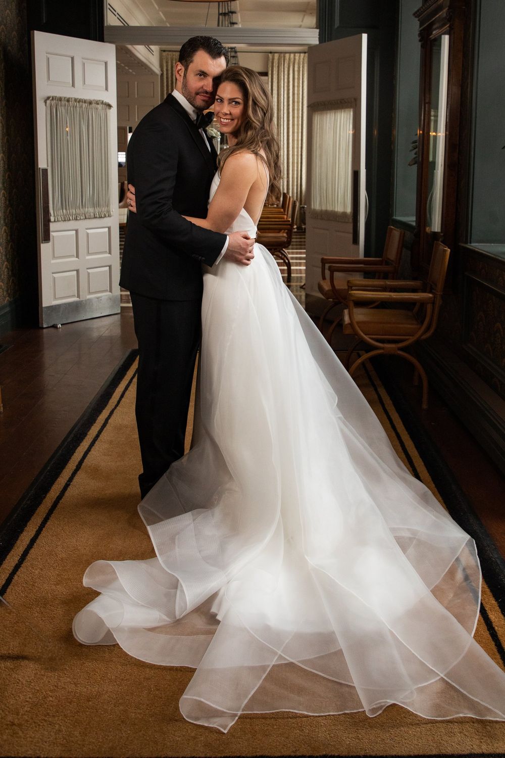 A romantic wedding portrait showcasing the bride's flowing white dress train in an elegant indoor setting.