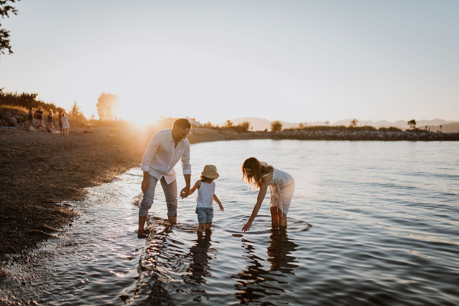 Family of three with Little boy standing in ocean at the Sunset at Jericho Beach