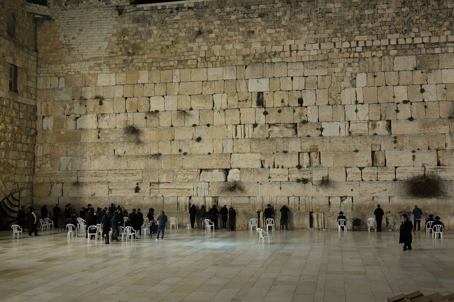People gathering at the Western Wall in Jerusalem at dusk.