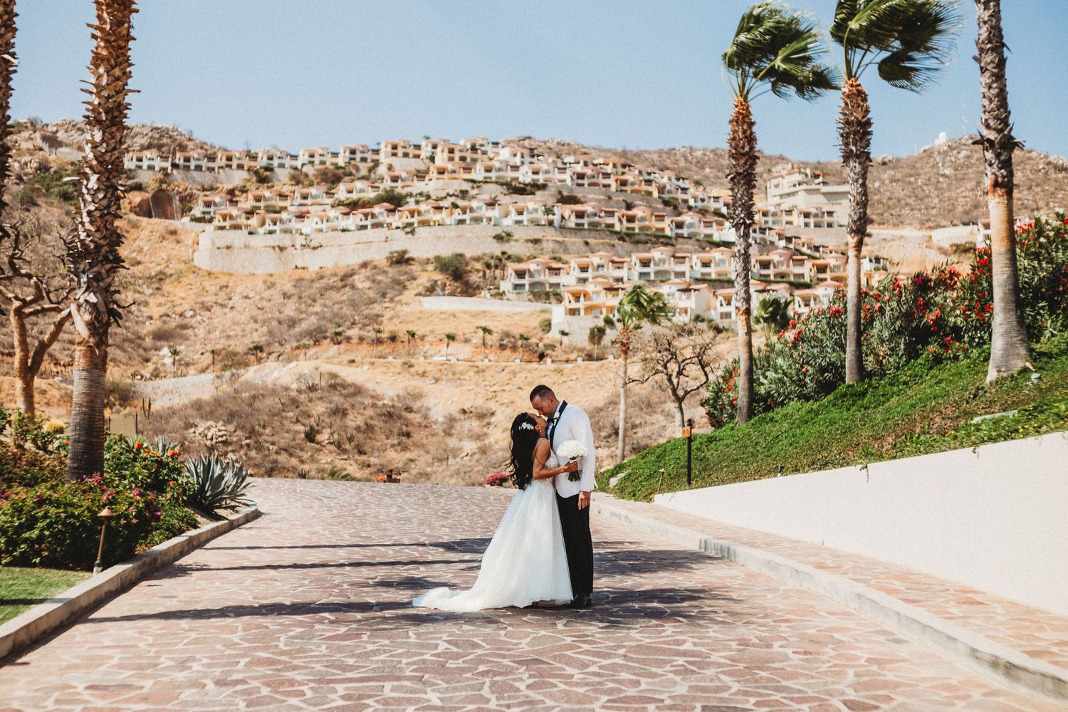 Couple touching foreheads as they post on a brick driveway in mexico after their wedding.