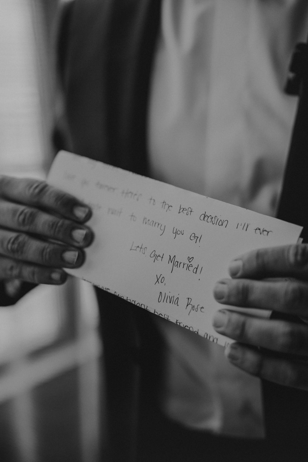 Hands holding a handwritten note or letter in black and white photography.