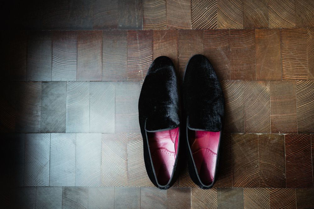 A pair of black formal leather loafers on a wooden parquet floor.