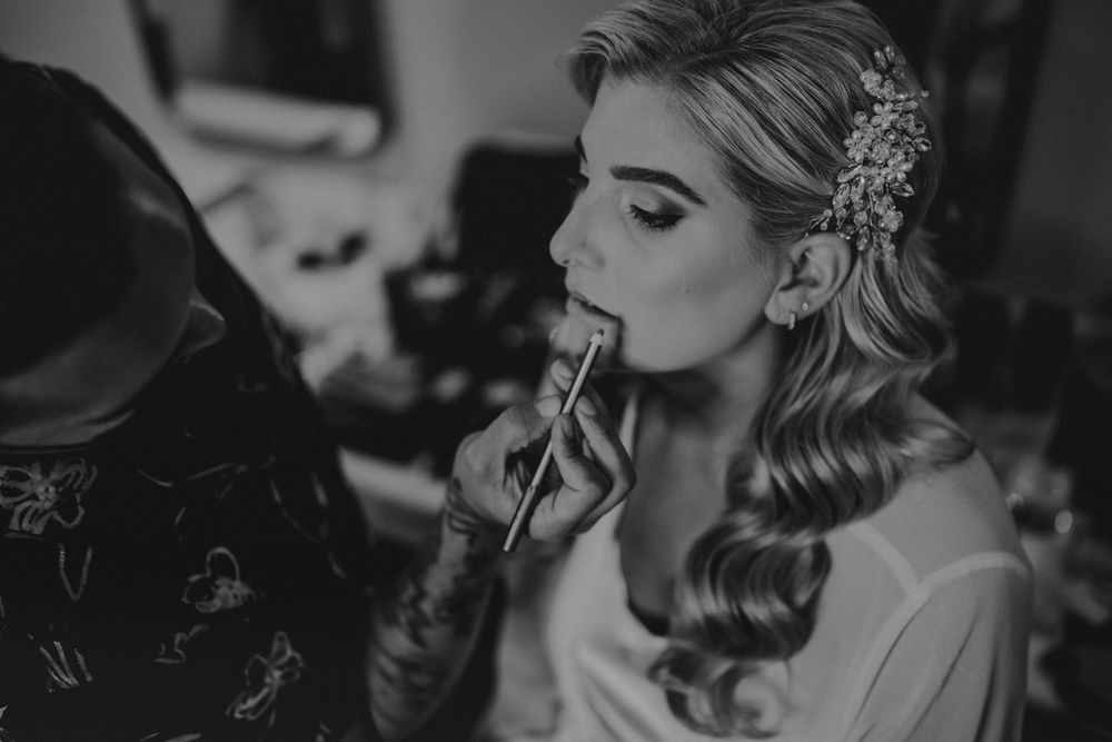 Professional makeup artist applying lipstick to a bride during wedding preparations.