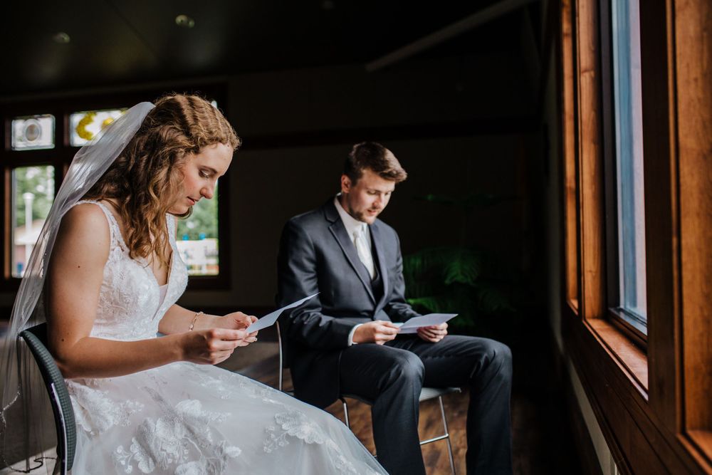 Couple sitting separately reading private letters before their wedding ceremony.