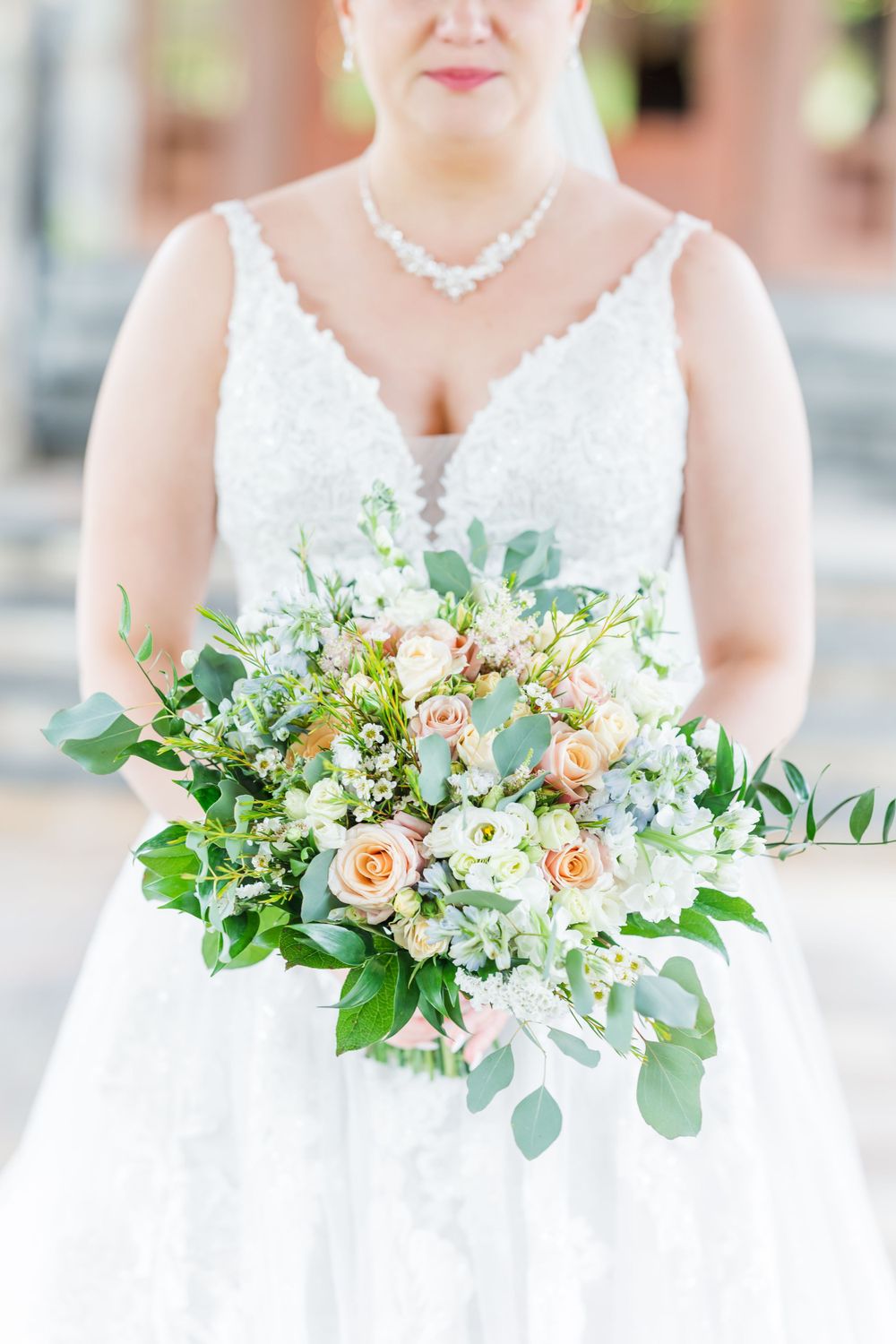 An elegant bridal bouquet featuring peach roses, white flowers and eucalyptus greenery.