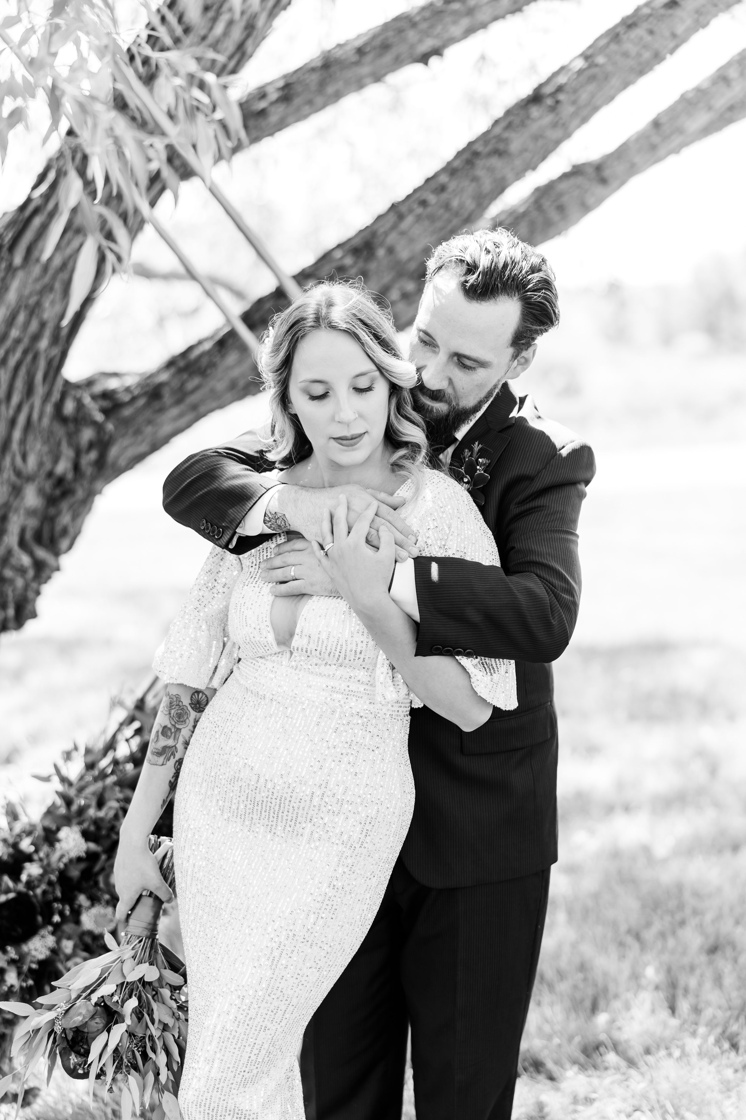 Romantic black and white portrait of a couple embracing under a tree.