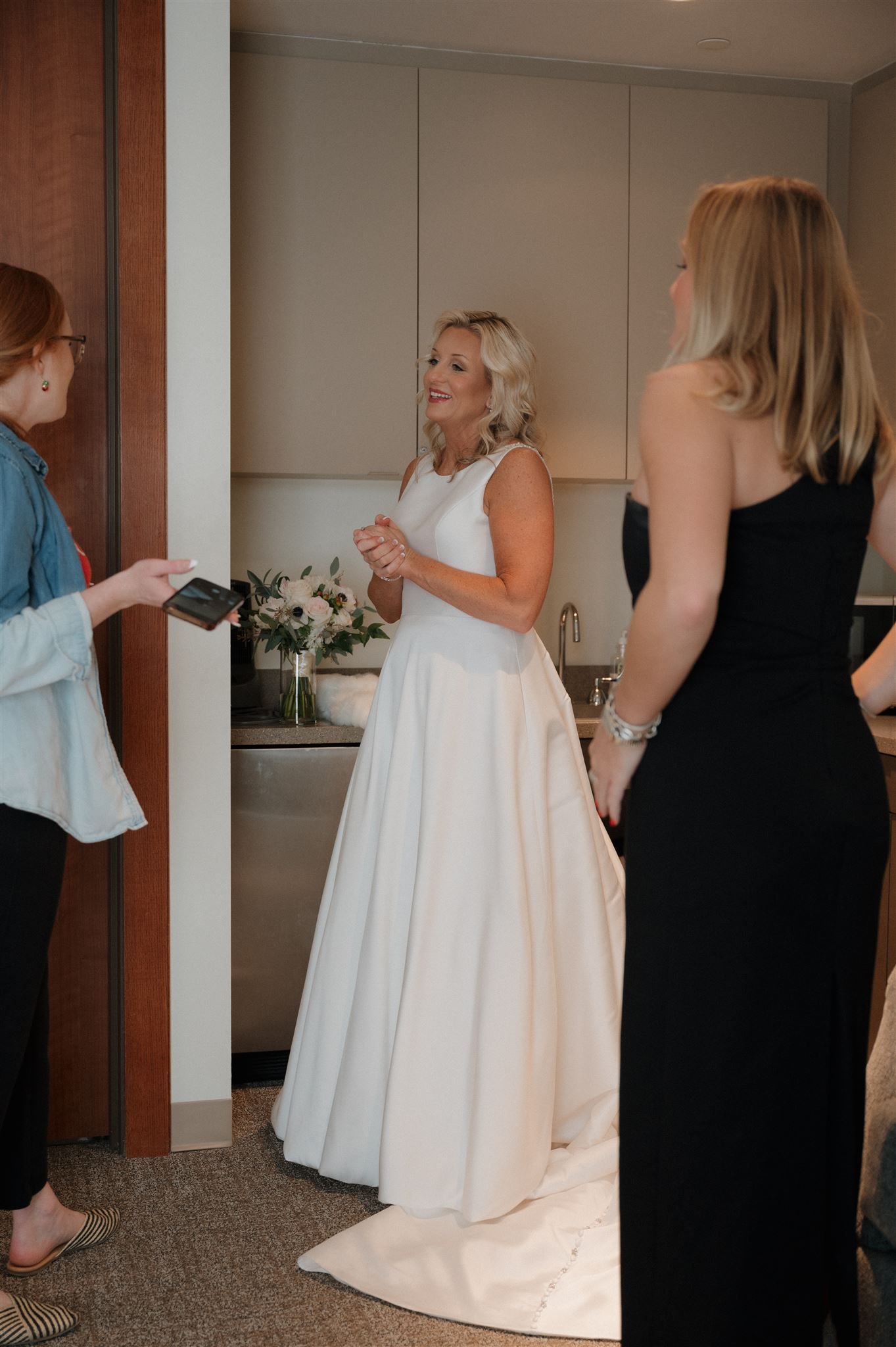Wedding preparations in a modern kitchen with attendants in black and white dresses.