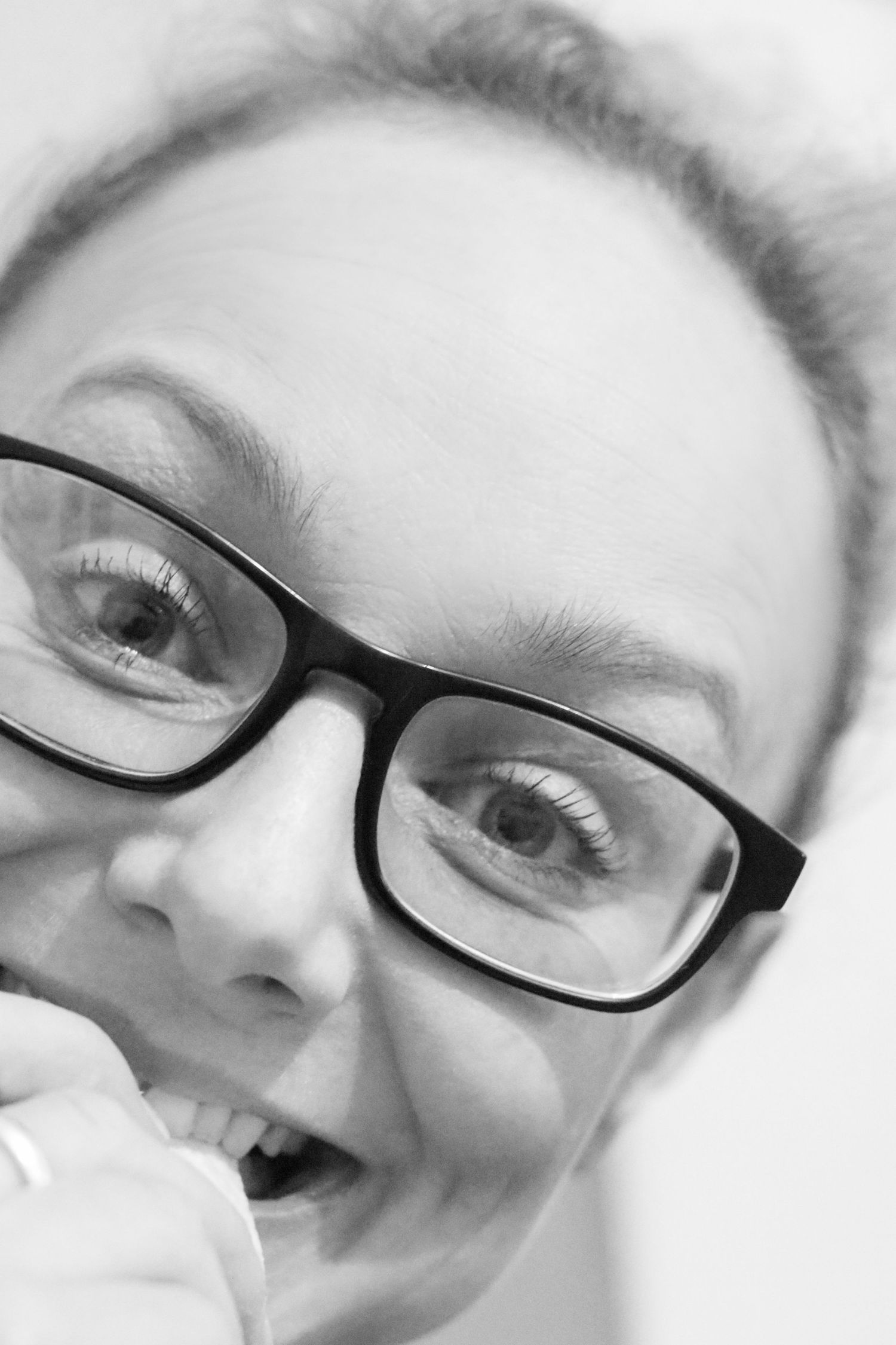photograph of Photographer Kate Leach in black and white looking at the camera with glasses on and finger in her mouth