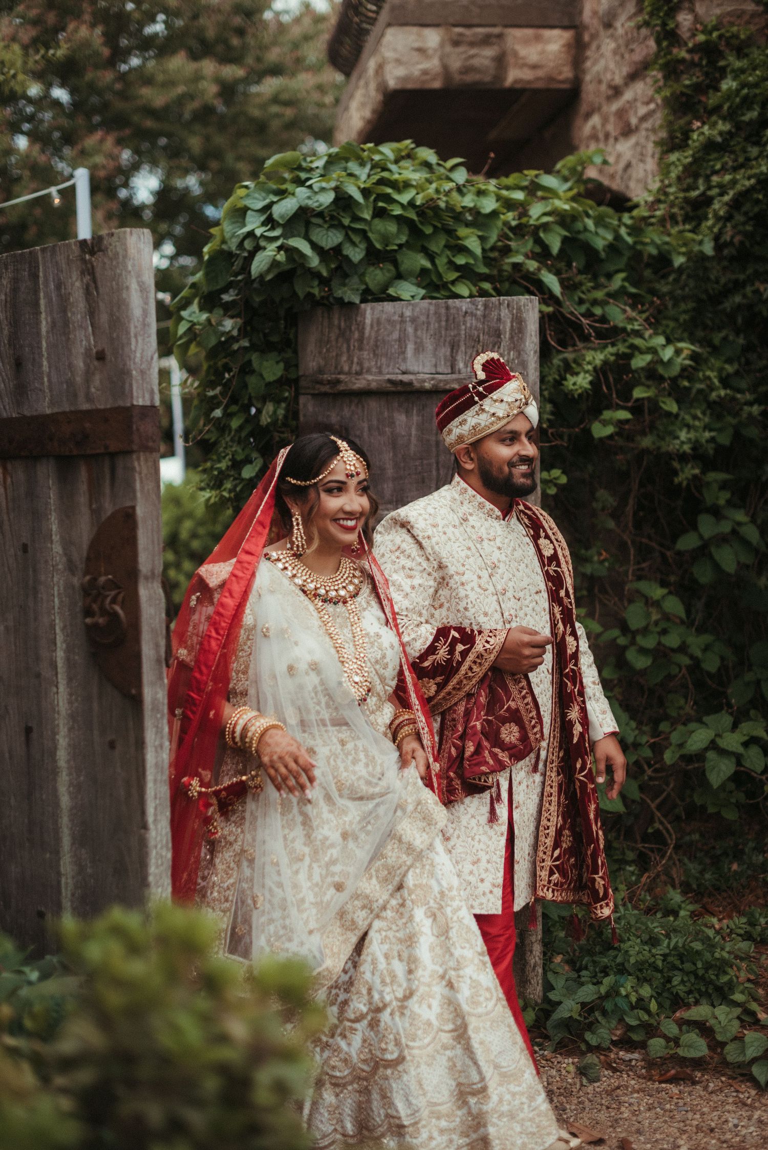A traditional South Asian wedding couple sharing a joyful moment in garden setting.