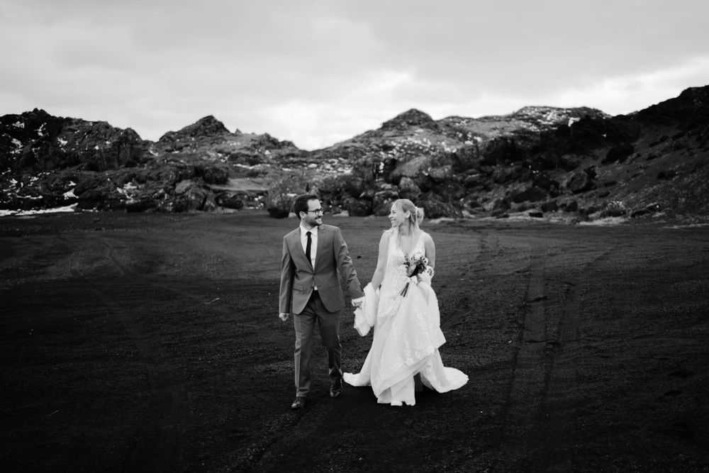 Black and white wedding photo with mountain backdrop on volcanic terrain.