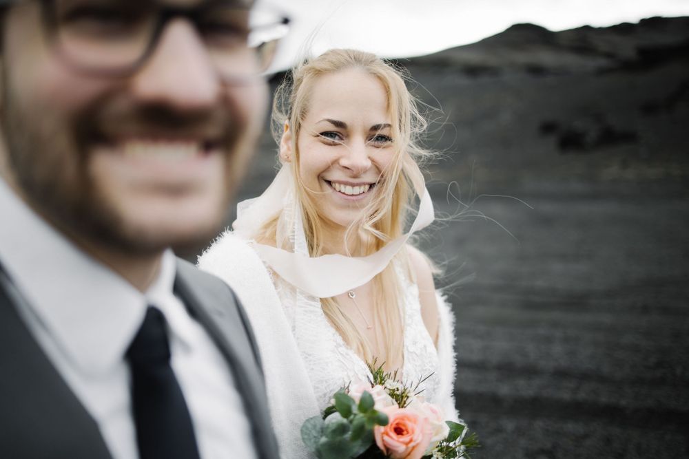 A candid wedding moment captured on dark volcanic terrain.
