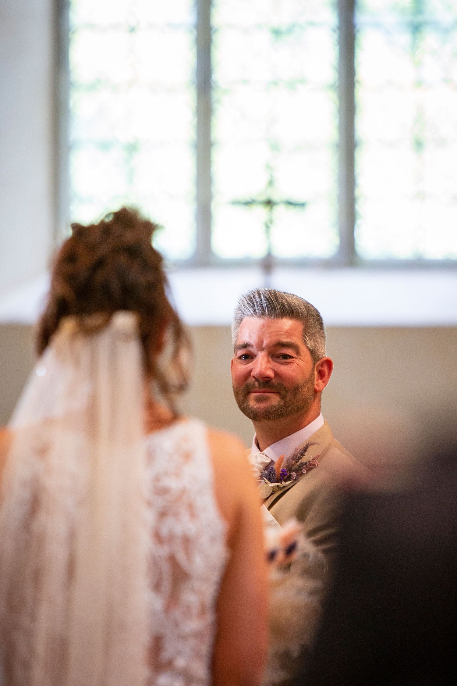 First look reaction captured in natural window light during intimate wedding ceremony.