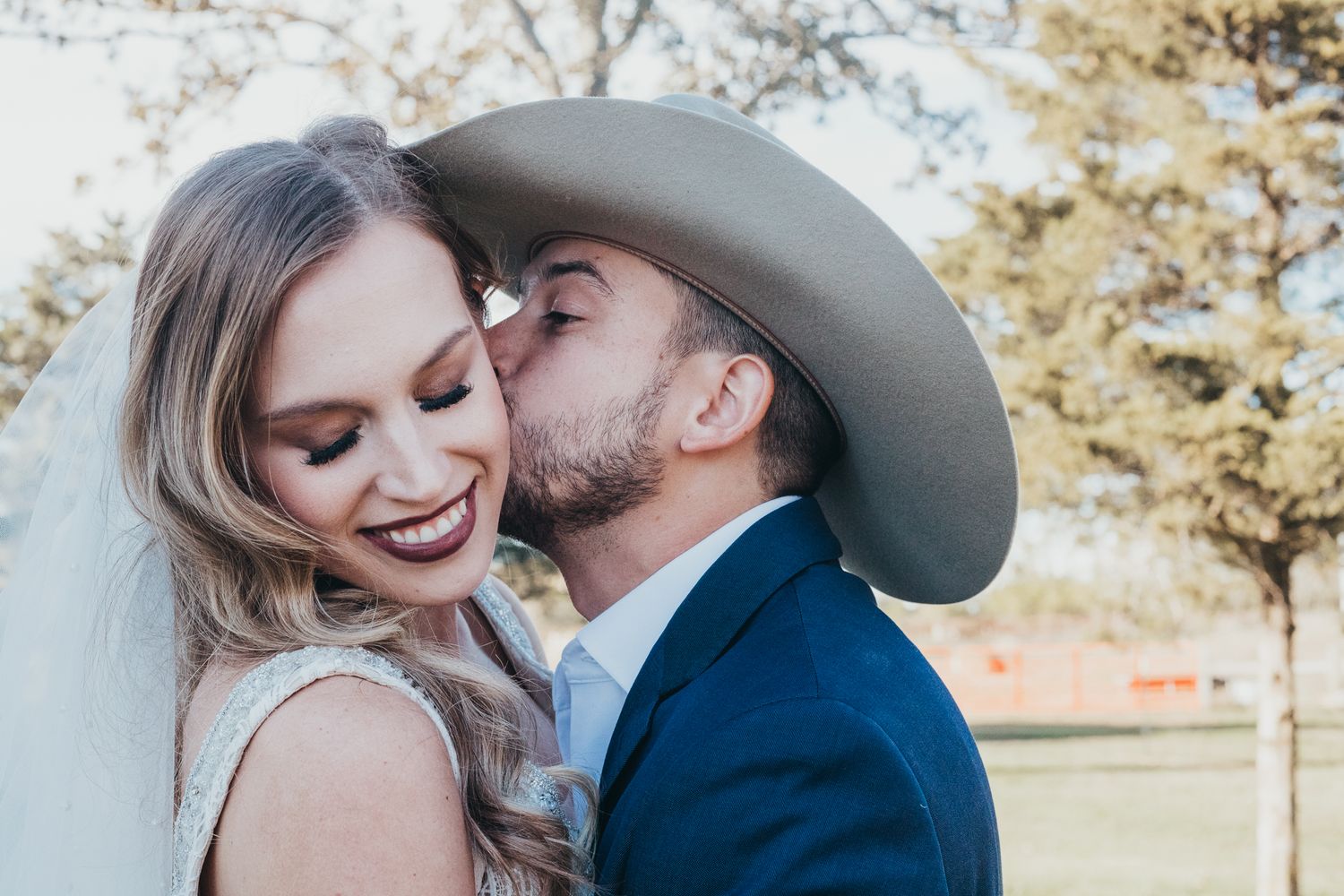 A romantic western-themed outdoor photo with a cowboy hat and navy suit against an autumn backdrop.