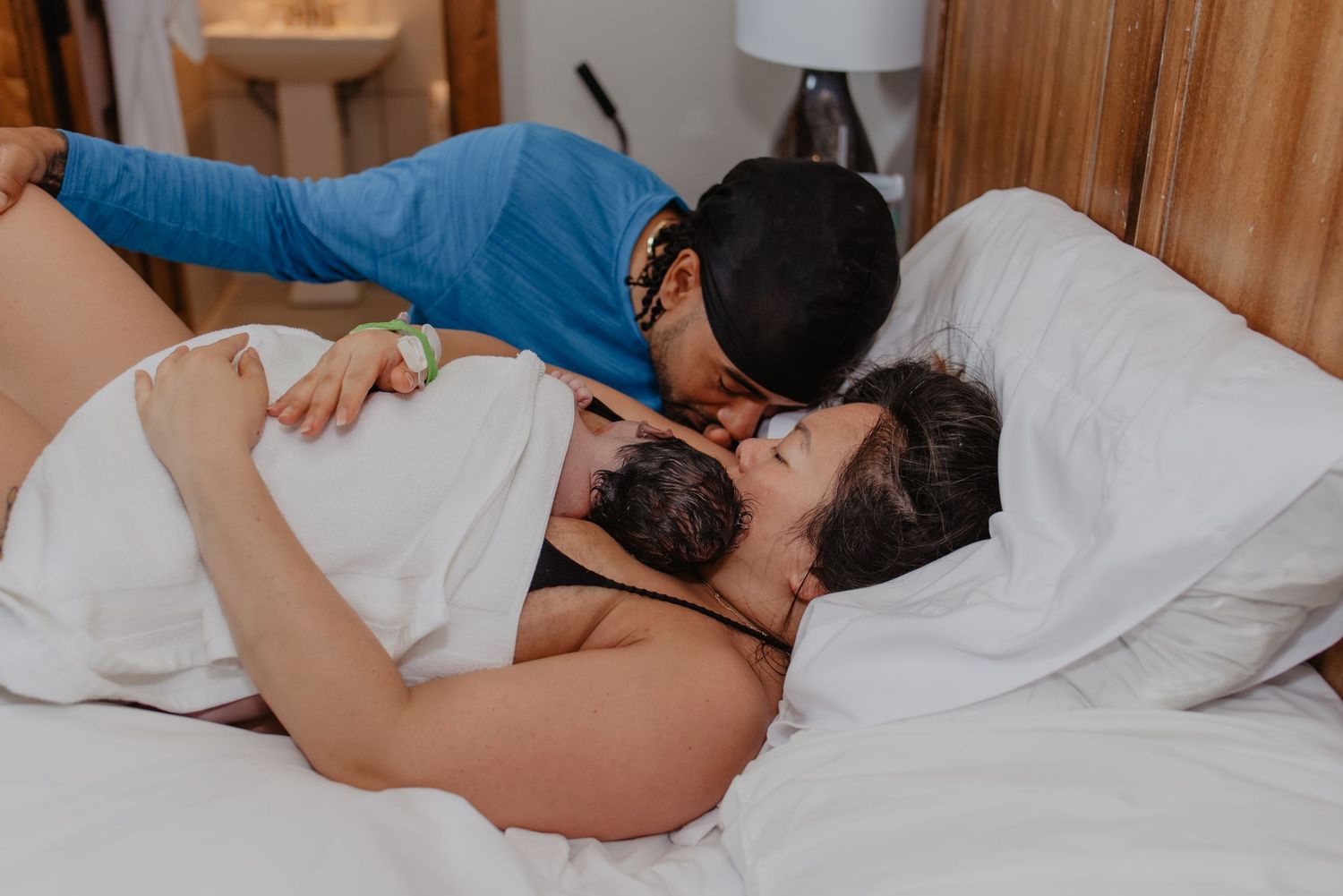 man crying at the sight of his wife, in bed, holding the baby she just gave birth to