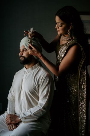 A candid moment during traditional South Asian wedding preparation in dramatic lighting.
