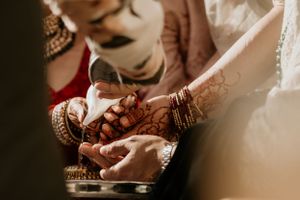 Close-up of intricate henna designs and wedding jewelry on hands.