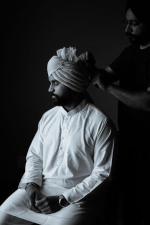 A black and white image showing turban styling preparation.