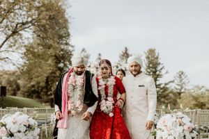 Newlywed couple walking together during outdoor Indian wedding ceremony with floral decorations.