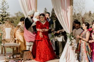Joyful celebration during South Asian wedding ceremony under decorated outdoor mandap.