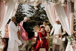 Joyful celebration under decorated wedding mandap with pink and white drapes.