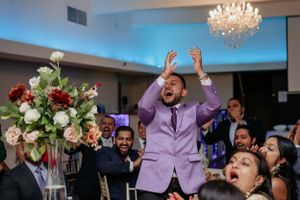 Energetic celebration at a wedding reception with crystal chandelier and floral arrangements.