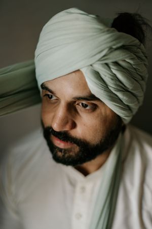 A close-up portrait showing traditional white turban styling.