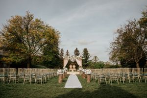 Outdoor wedding ceremony setup with white chairs and gazebo surrounded by autumn trees.