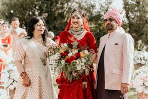 Traditional South Asian wedding celebration with colorful attire and floral arrangements outdoors.