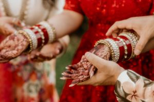 Ornate bridal bangles and jewelry adorning hands decorated with traditional mehndi designs.